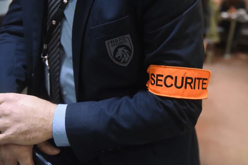 Sécurité et gardiennage à Marrakech, Maroc : Membre du personnel portant une veste sombre 'HARD SECURITE' avec un logo visible.